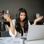 a confused woman looking at her laptop